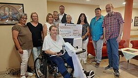 Spende der Bürgerstiftung Langenzenn an die AWO Menschen um eine Person mit Spendenscheck für das AWO-Seniorenheim in Langenzenn